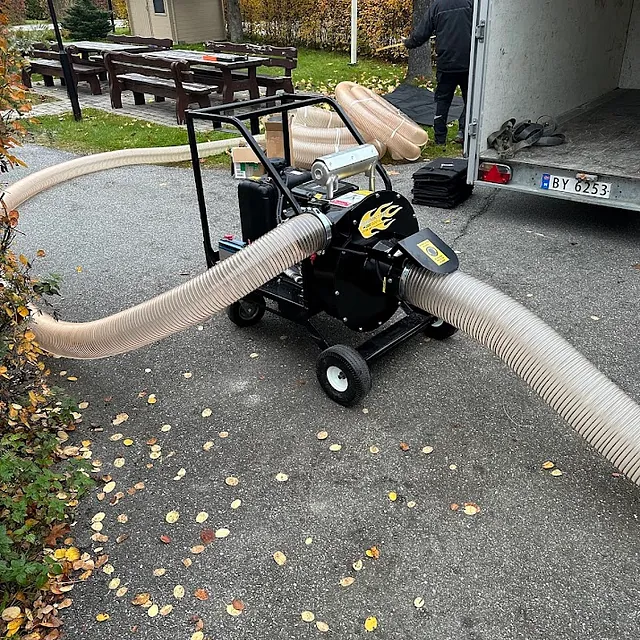Isolasjonsmaskin med slange på en gårdsplass.